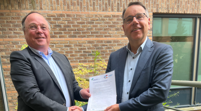 Directeur Vewin en directeur Energie Nederland schudden hand en houden ondertekend contract vast
